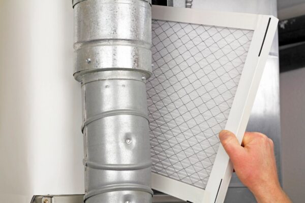 Homeowner replacing an HVAC air filter to improve air conditioning efficiency in Kaufman, TX